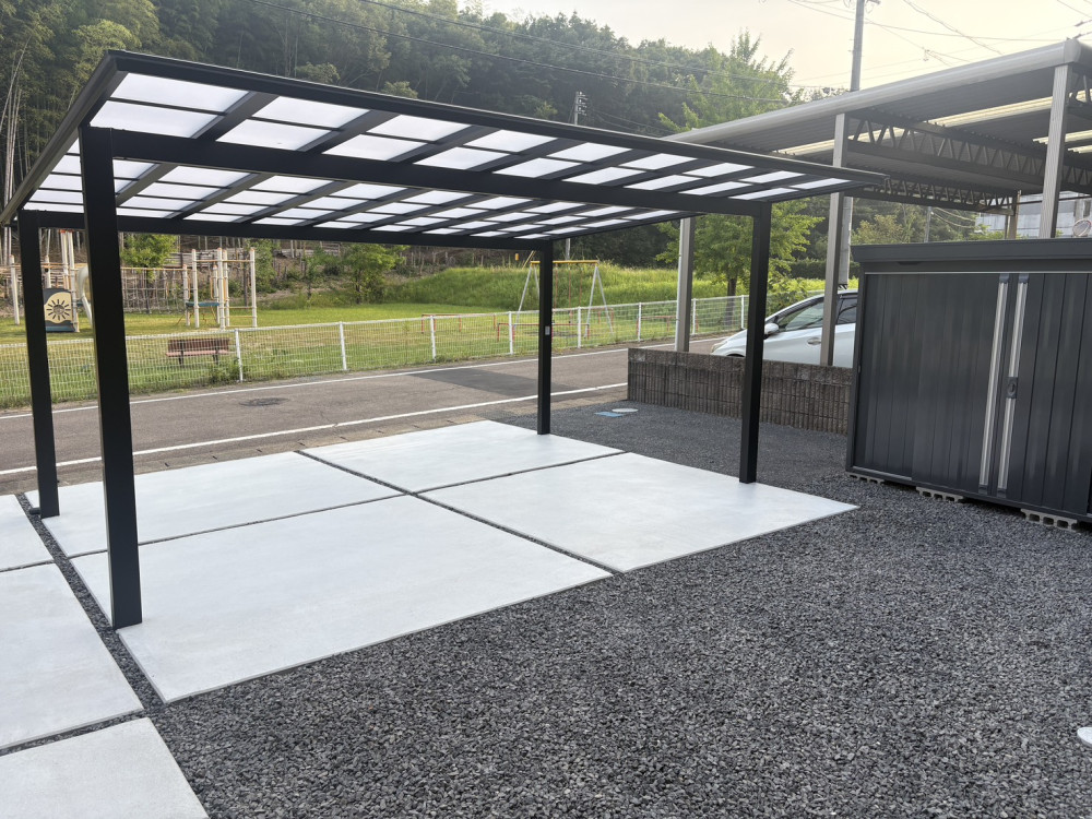 LIXIL「ネスカF」2台用のカーポートと土間コンクリート。イナバ物置「フォルタ」や三協アルミ「マイエリアⅡ」、防草シート・砂利敷までまとめて施工し、ブラックを基調とした統一感のある新築外構に仕上げました。