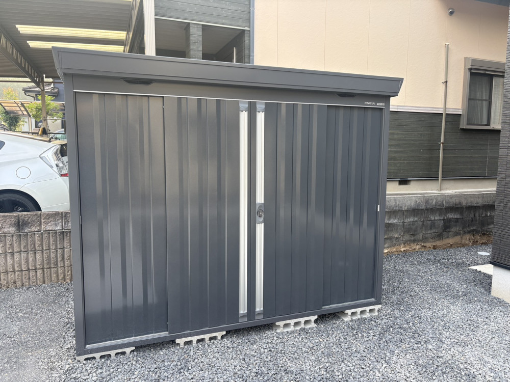 LIXIL「ネスカF」2台用のカーポートと土間コンクリート。イナバ物置「フォルタ」や三協アルミ「マイエリアⅡ」、防草シート・砂利敷までまとめて施工し、ブラックを基調とした統一感のある新築外構に仕上げました。