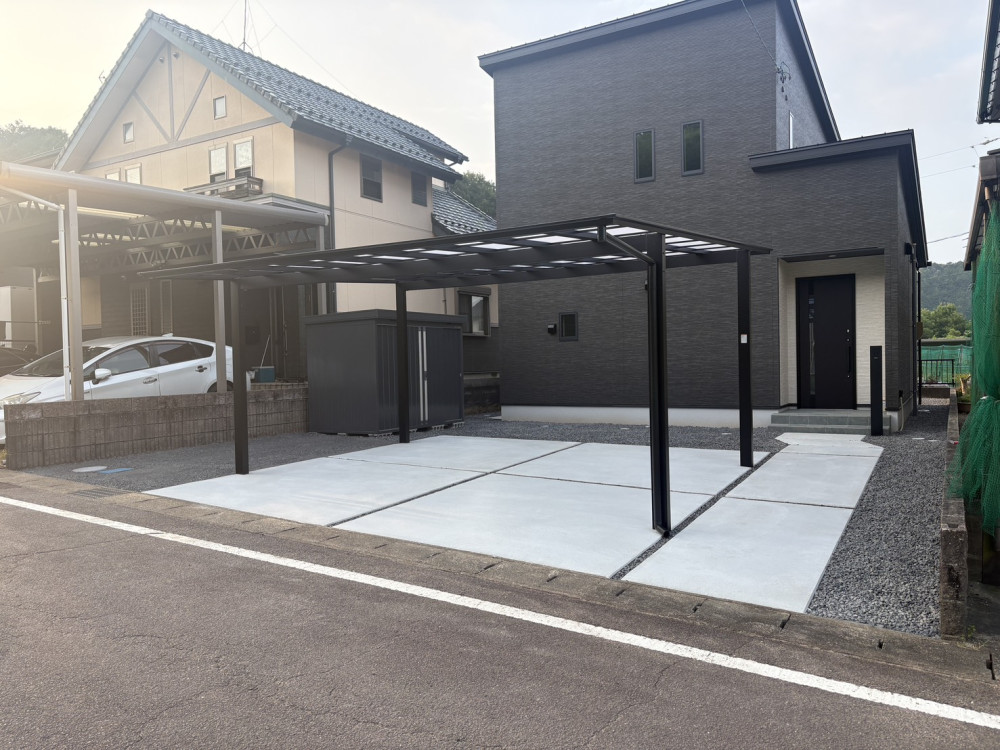 LIXIL「ネスカF」2台用のカーポートと土間コンクリート。イナバ物置「フォルタ」や三協アルミ「マイエリアⅡ」、防草シート・砂利敷までまとめて施工し、ブラックを基調とした統一感のある新築外構に仕上げました。